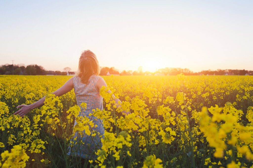 photo of a happy young woman enjoying summer in yellow field at sunset, conveys mindfulness and empathy